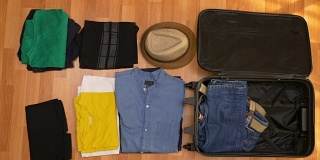 俯视图旅游的概念，游客有序地打包他的衣服到手提箱
