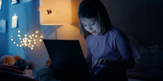 聪明的年轻女孩在她的卧室深夜坐在她的床上笔记本电脑和键入一些有趣的东西。她的夜灯开着。