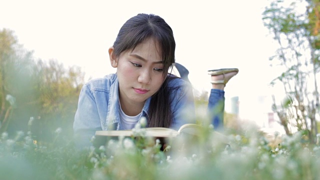 年轻的亚洲女孩在公园看书