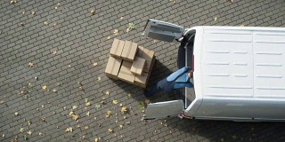 送货员用硬纸板箱装载他的商业货车。加快视频。