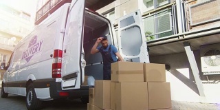 年轻的搬运工用大纸板箱装载他的商务车。