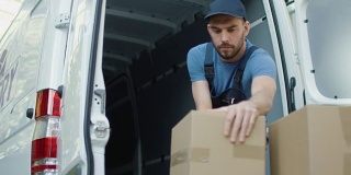 年轻的搬运工用纸板箱装载他的货车