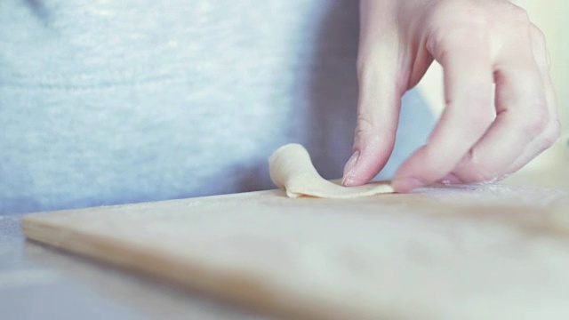 女人们的手在擀面团，准备包饺子。厨师在室内厨房里煮饺子