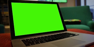 一般的笔记本电脑在酒店大堂等候区，有绿色屏幕的角钉