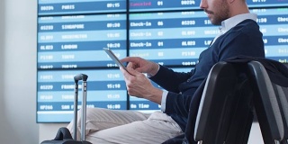 一名男子在机场候机室等候登机时使用平板电脑。