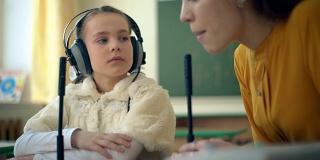 小女孩和老师在教室里使用耳机和麦克风