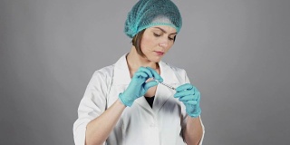年轻女医生戴手套，拿着注射器，准备注射隔离在灰色背景。医疗保健的概念。在4 k拍摄