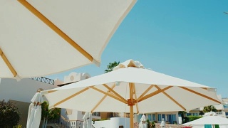 豪华酒店的绝佳休息。一排雪白的雨伞映衬着蓝天的背景。替身拍摄视频素材模板下载