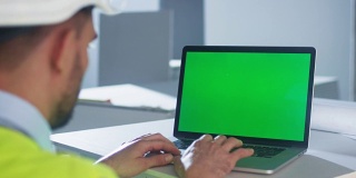 工程师在建筑内部使用带绿屏的笔记本电脑。伟大的模型使用。