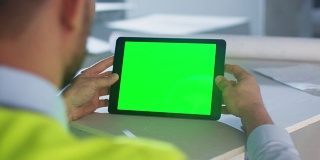 工程师手持绿色屏幕平板电脑在建筑内。伟大的模型使用。