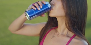 年轻女子喝能量饮料。亚洲女人喝汽水罐