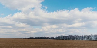 在早春的时候沿着犁过的田地快速行驶。可见的农田和蓝天白云。POV窗板视频，3轴稳定