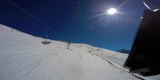从上到下的雪坡，痕迹，滑雪者和降落伞从椅子升降机。第一人称视角