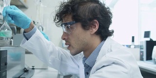 身穿大衣的多民族学生团队在化学教室实验室工作。