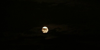 一轮满月穿过乌云划过黑暗的天空。延时。4K，超高清，超高清