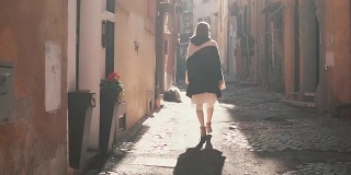 一个年轻的女游客在阳光明媚的日子里走在一条小街上。女孩在欧洲度假，探索古城