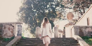 年轻时尚的女子走在城市老街上，爬着楼梯。在欧洲度假的女孩