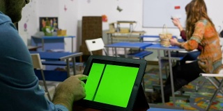 年轻的企业家在培训室内使用绿色屏幕的平板电脑