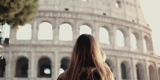 年轻的黑发游客探索罗马斗兽场，意大利。女人用智能手机拍照