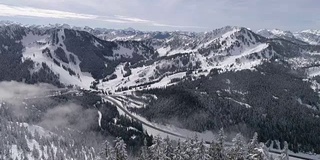 惊人的航拍显示高速公路到冬季滑雪胜地与雪山山峰