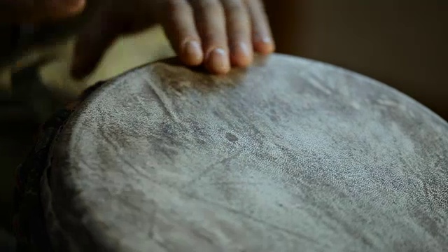 一个男人的手在一个非洲皮肤覆盖的手鼓上敲出一个节拍。