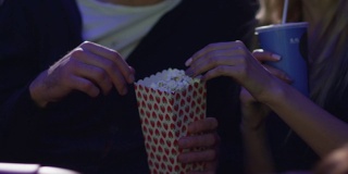 一对年轻的浪漫情侣手牵着手在电影院看电影。