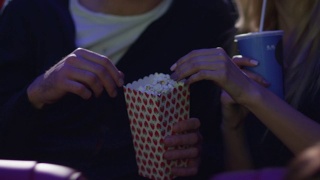 一对年轻的浪漫情侣手牵着手在电影院看电影。视频素材模板下载