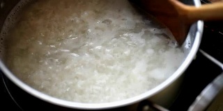 在不锈钢锅中加入开水，用木勺将米饭混合