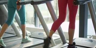 迷人的白人女孩在跑步机上跑步粉红衣服在体育健身馆。