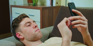 躺在沙发上玩手机的男人