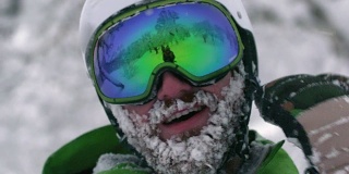 戴着头盔的滑雪者滑雪者登山运动员大胡子满是雪花从冰冻的脸上摇下来