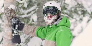 滑雪者或滑雪板戴头盔护目镜绿色夹克吃雪冰冻的雪胡子快乐的生活方式山森林
