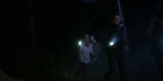 夜里，人们拿着手电筒在森林里跑来跑去。