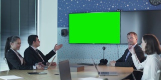 团队员工在会议室交谈。墙上的模型用绿屏显示。