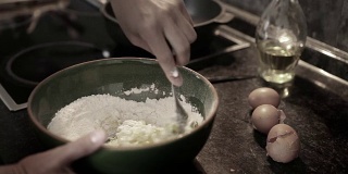 一名厨师将鸡蛋和面粉混合在碗里揉面团的静音实时视频