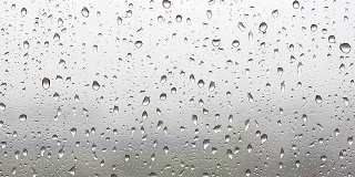 Drops of rain flow down the window glass