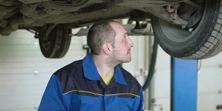 在汽车维修服务中，汽车修理工正在检查跨界车的汽车悬架