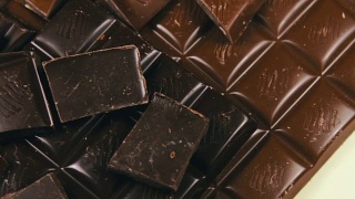 木背景上的牛奶和黑巧克力瓷砖。巧克力棒结束了视频素材模板下载