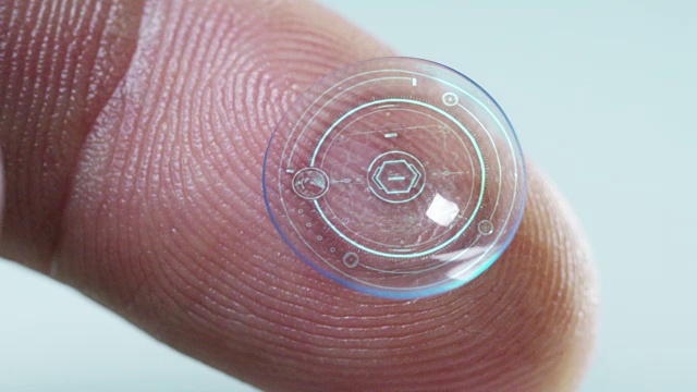 微距拍摄的手指持有的隐形眼镜技术与芯片，以看到更好的双眼和增加屈光度。概念:眼检、光学、沉浸式技术