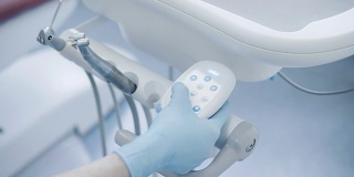 特写医生的手按下牙医椅上的按钮，切换模式。牙医手术