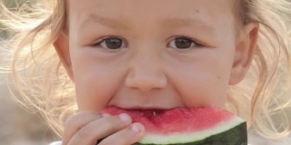 小可爱的小女孩在日出时吃红西瓜的特写