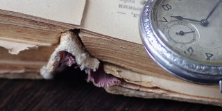 旧怀表放在褪色的旧书旁边，