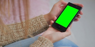 一个女人在看绿色屏幕的智能手机