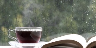 下雨天窗户上的咖啡杯和书