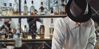 戴黑帽子的专业调酒师正在酒吧里调鸡尾酒