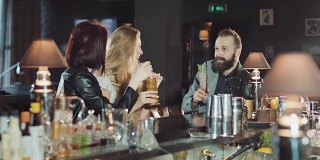 3个快乐的积极的朋友在晚上庆祝酒吧，碰杯和有趣的交谈在一起