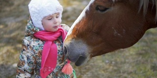 一个小女孩正在抚摸和亲吻那匹马。慢动作