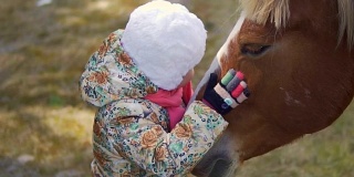 一个小女孩抚摸着马，把自己的脸贴在马身上。慢动作