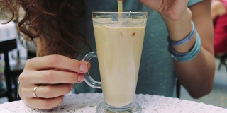 在夏日的咖啡馆里，女孩用吸管喝着冰凉的冰咖啡，慢镜头