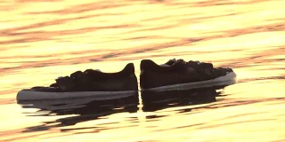 特写:在金色的夕阳下，湿滑的滑板鞋漂浮在水面上